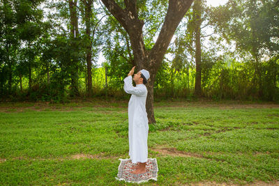 Asian muslim praying jamaah on green meadow.