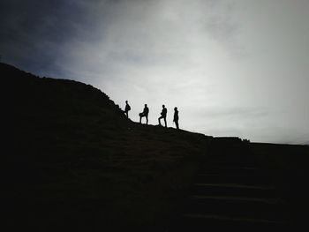 Low angle view of silhouette men hiking on mountain