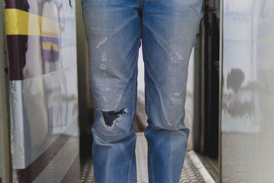 Midsection of woman with torn jeans standing indoors