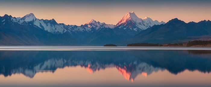 Scenic view of lake and mountains against sky during sunset