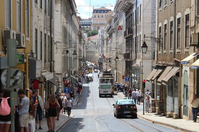 People walking on road amidst buildings in city