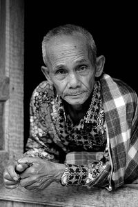 Close-up portrait of man leaning on window