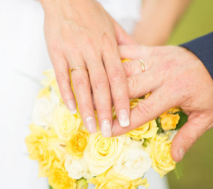 Cropped hands of couple on yellow roses at wedding ceremony