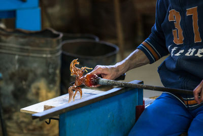 Midsection of man making glass horse figurine in workshop