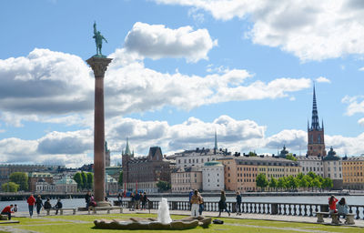 Statue in city against cloudy sky