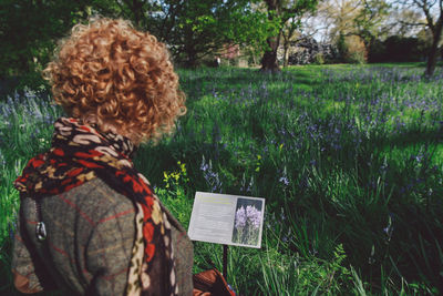 Woman reading information sign against plants at forest