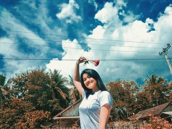 Low angle view of woman standing by plants against sky