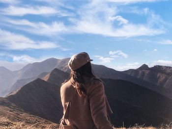 Rear view of woman looking at mountain range against sky