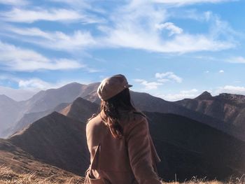 Rear view of man looking at mountain range against sky