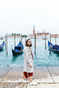 Young tourist in dress and coat on canal and venetia gondola