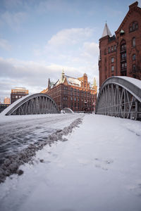Bridge over river by buildings against sky