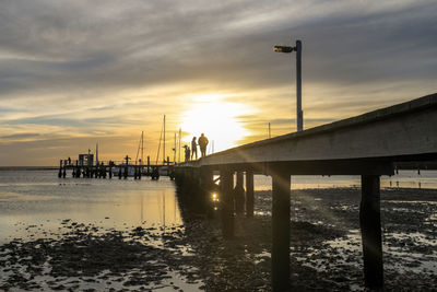 Pier over sea against sky during sunset