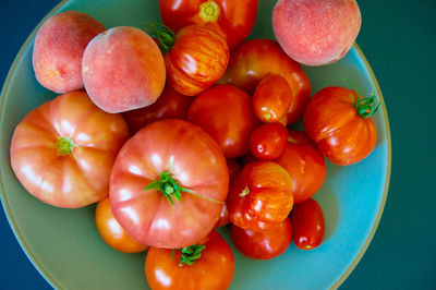 Close-up of fresh tomatoes and peaches in plate on table
