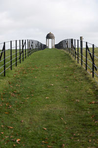 Wooden posts on footpath by sea against sky