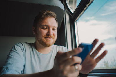 A man using a smartphone while traveling by railway train