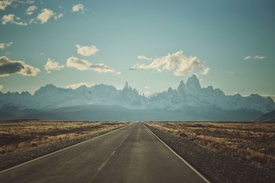 Road leading towards mountains against sky