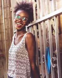 Portrait of smiling young woman standing by gate