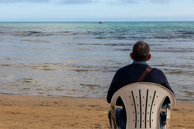 Rear view of man sitting on beach