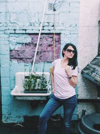 Mid adult woman wearing sunglasses standing against wall