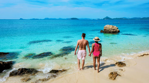 Rear view of woman standing at beach