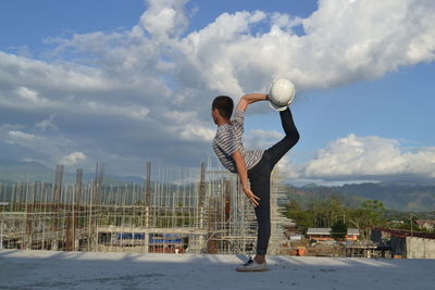 Full length of boy standing on ball against sky
