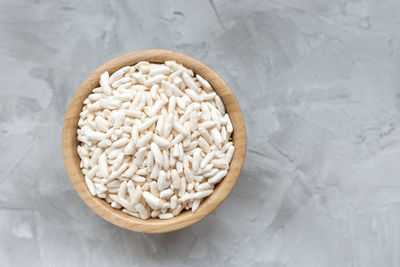 Puffed rice in a wooden bowl on a gray background,  copy space 