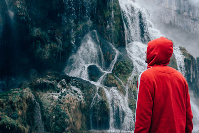 Rear view of man standing by waterfall