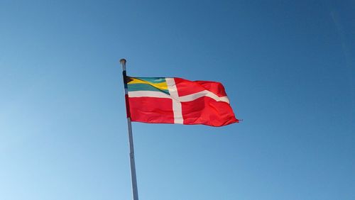 Low angle view of flag against clear blue sky