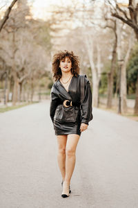 Portrait of young woman standing on footpath