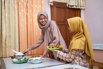 Smiling mother and daughter having food at home