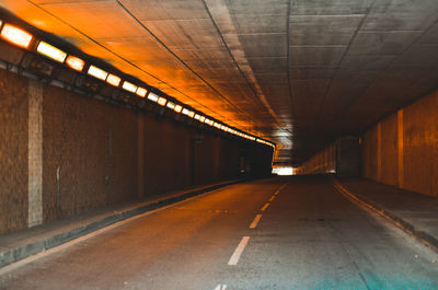 Empty road in illuminated tunnel