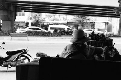 Rear view of person sitting on bench in city