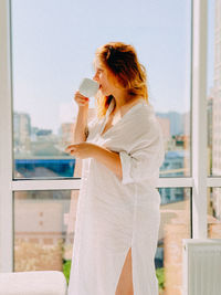 Side view of young woman drinking glass