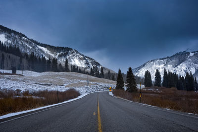 Road amidst snowcapped mountains against sky during winter