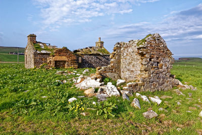 Old ruins of building on field against sky