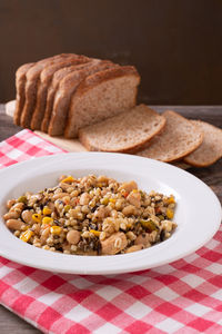 Spelled, chickpea, tuna and corn salad arranged on rustic table with bread