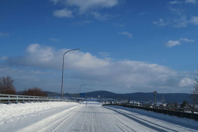 Road by snow covered city against sky