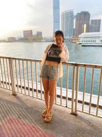 Portrait of young woman standing on railing