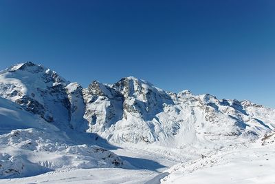 Scenic view of snowcapped mountains against clear blue sky