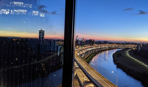 Aerial view of illuminated bridge and buildings in city at night