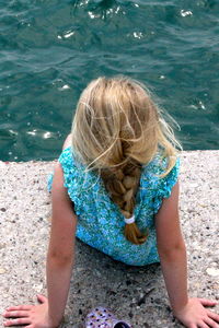 Rear view of girl sitting on pier against lake