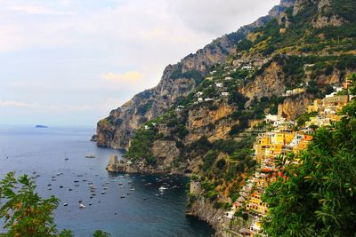 Positano village on mountain by sea against sky