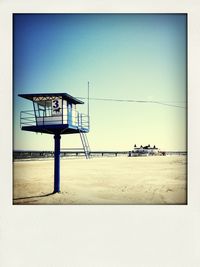 Lifeguard hut on beach against clear blue sky