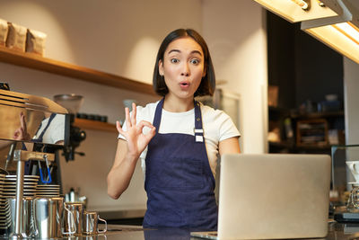 Portrait of young woman using mobile phone while sitting at home