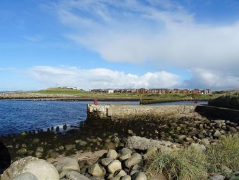 Scenic view of rocks by river against sky