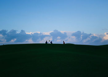 People on golf course against sky