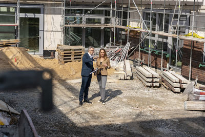 Engineer having discussion with colleague while standing at construction site