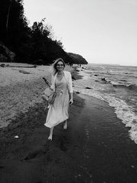 Woman standing at beach against sky