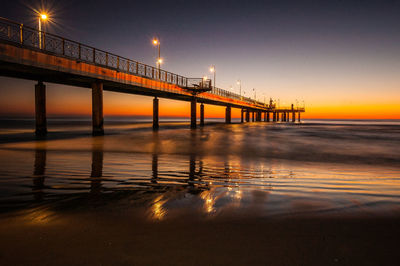 Bridge over sea against sky during sunset