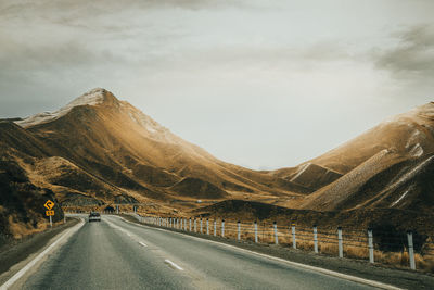 Empty road along mountain range against sky